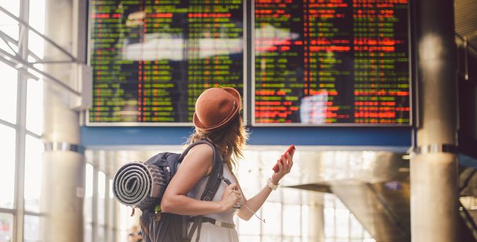 Alleinreisende Frau schaut auf einen Zeitplan am Bahnhof