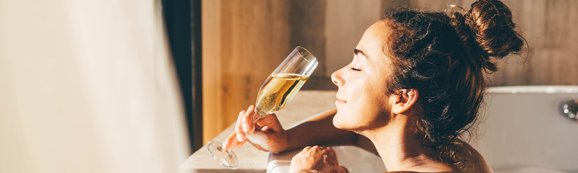 Eine Frau lehnt am Rand eines Whirlpools und genießt ein Glas Sekt