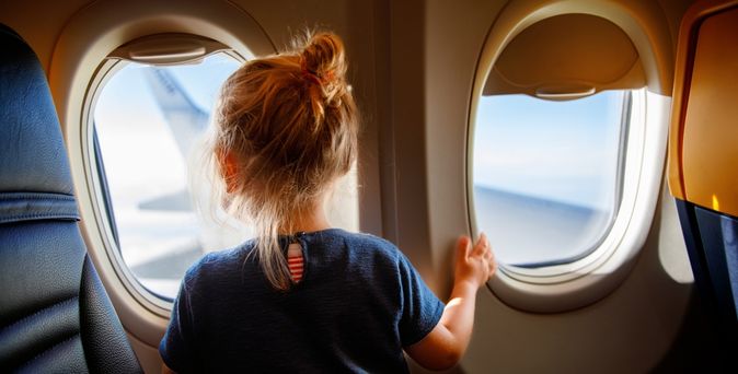 Mädchen schaut aus dem Fenster eines Flugzeuges