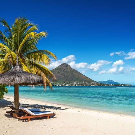 Zwei Liegen unter einem Schirm am Strand