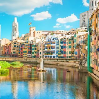 Blick von einer Brücke auf den Fluss Onyar in Girona mit bunten Häusern an der Costa Brava in Spanien