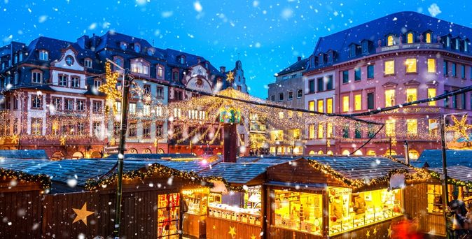 Hell erleuchtete Buden eines Weihnachtsmarktes mitten in einer Stadt