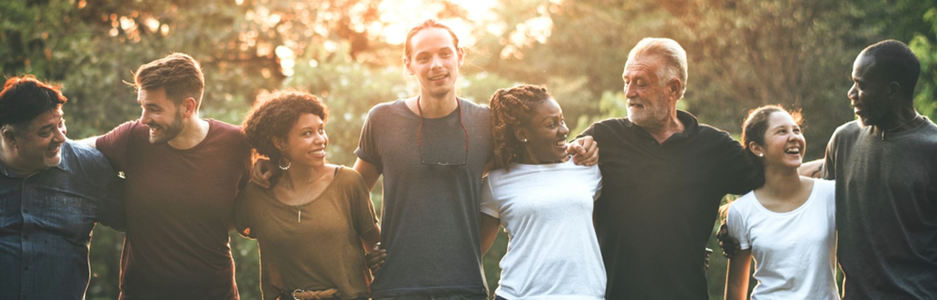 Eine Gruppe von Menschen steht Arm in Arm draußen in einer Reihe
