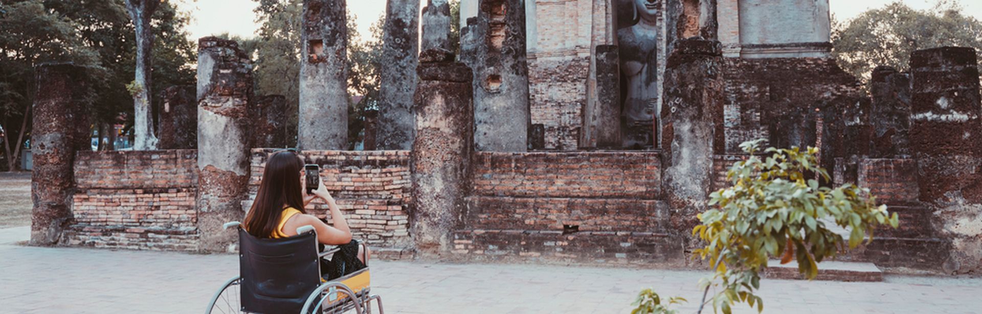 Frau im Rollstuhl fotografiert ein altes Bauwerk