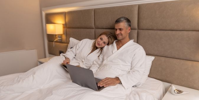 Ein Paar sitzt im Bett und schaut gemeinsam auf einen Laptop