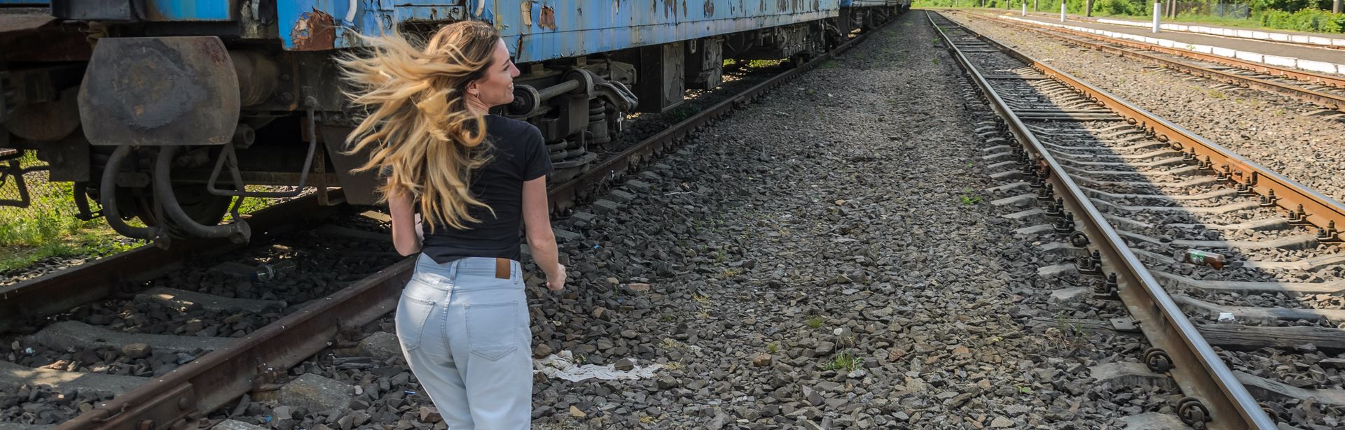 Frau läuft zu einem Zug zwischen den Gleisen