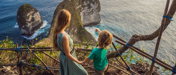 Mutter und Kind schauen von einer Treppe aus auf das Meer