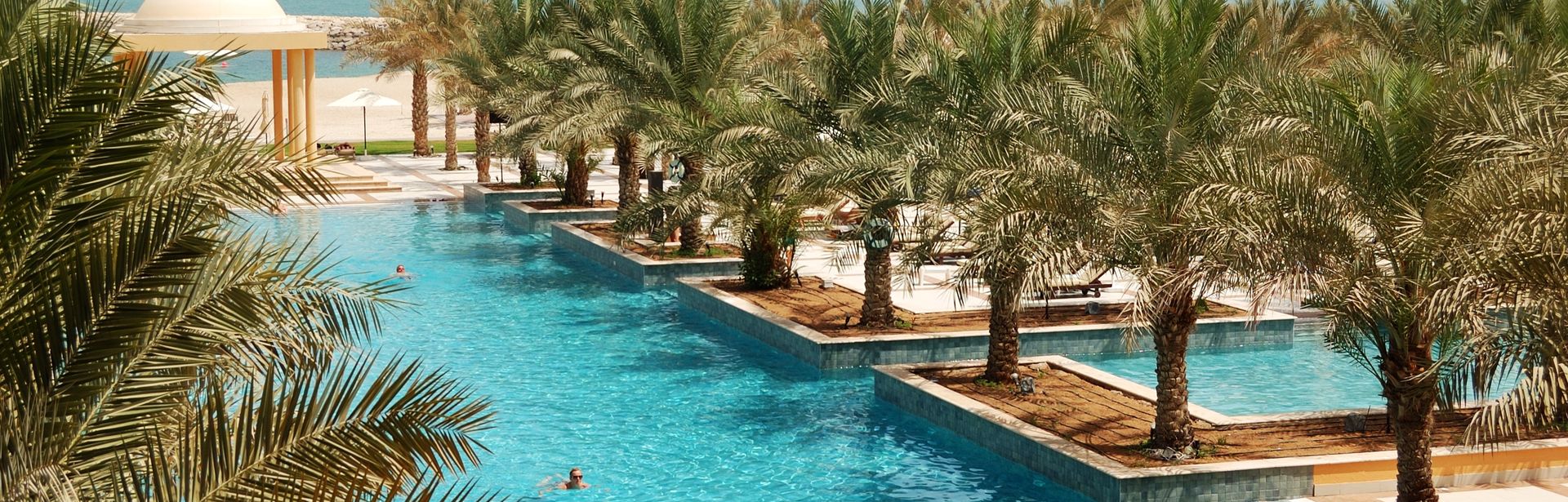 Poollandschaft mit Palmen und Blick auf das Meer