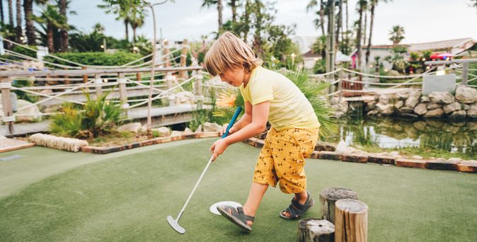 Junge spielt Minigolf