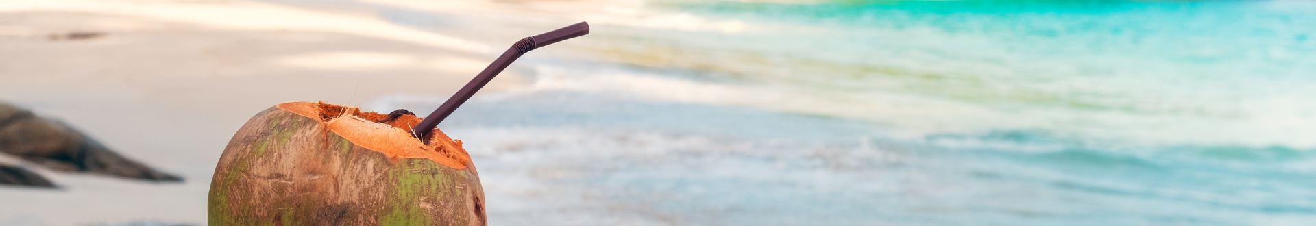 Kokosnuss mit einem Strohhalm steht am Strand