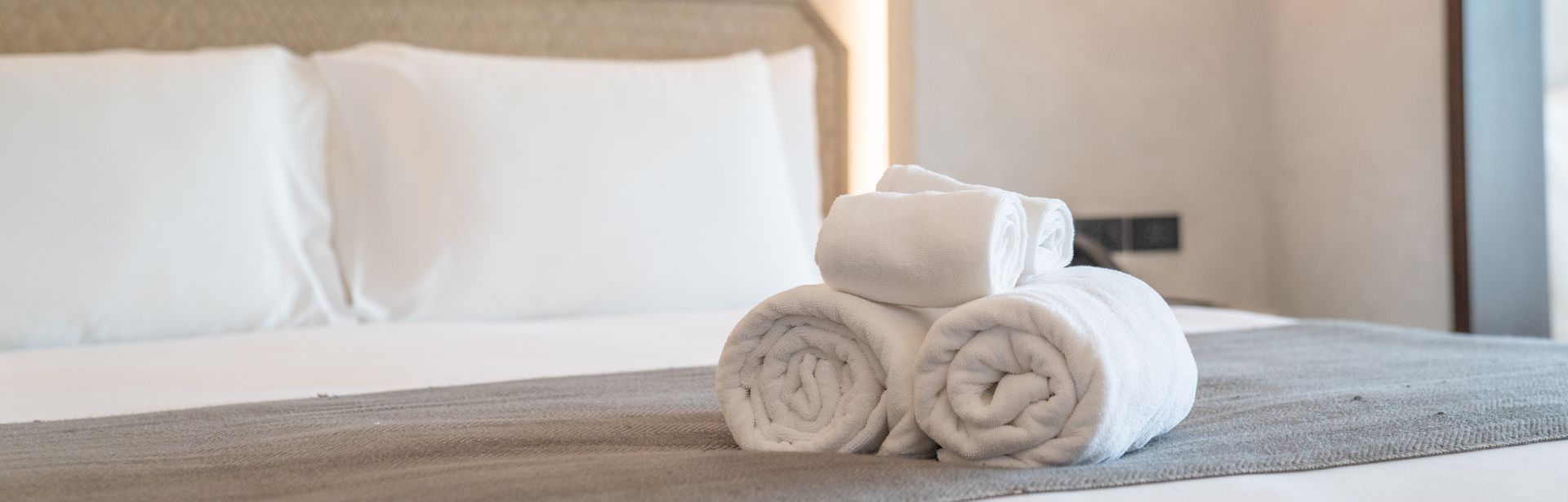 Aufgerollte Handtücher auf einem gemachten Bett