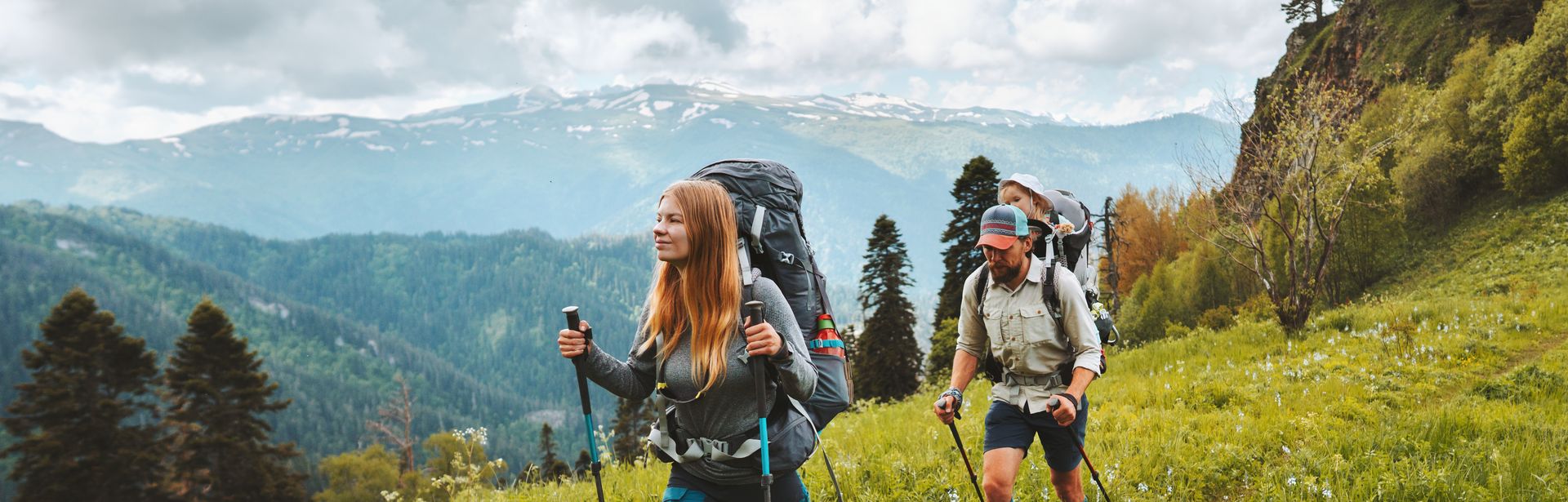 Zwei Personen wandern mit Nordic Walking Stöckern durch eine Wiese