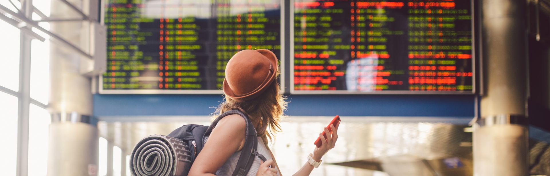 Alleinreisende Frau schaut auf einen Zeitplan am Bahnhof