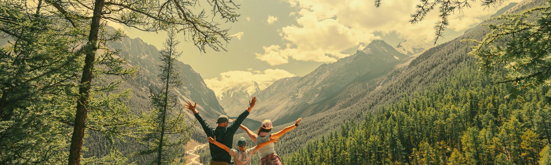 Eltern und Kind schauen beim Wandern gemeinsam auf eine Berglandschaft 