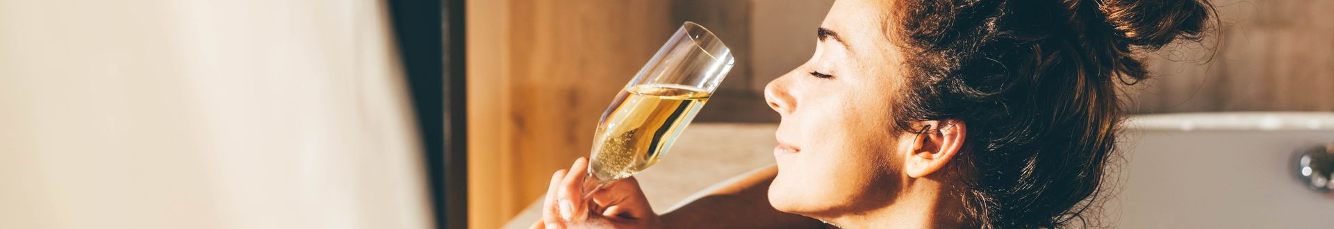 Eine Frau lehnt am Rand eines Whirlpools und genießt ein Glas Sekt