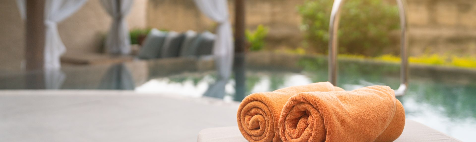 Aufgerollte Handtücher auf einer Liege am Pool