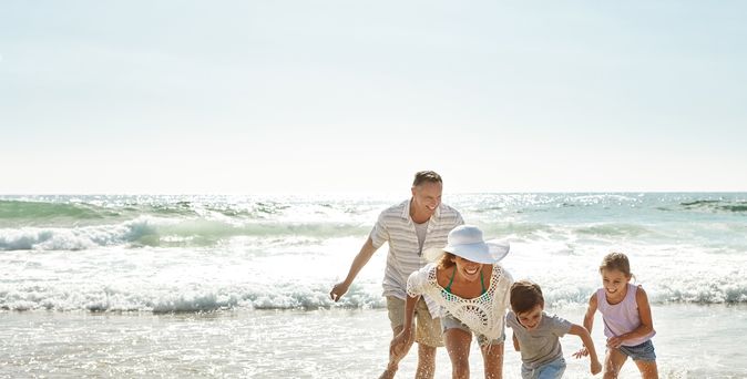 Eine Familie am Strand läuft lachend durch das Wasser