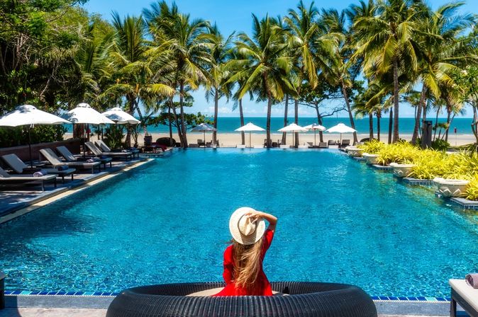 Eine Frau sitzt am Pool mit direktem Strandzugang