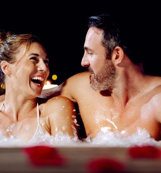 Ein Paar schaut sich im Whirlpool an bei Kerzenschein