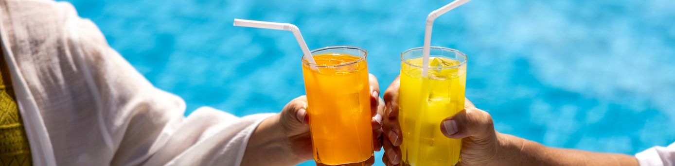 Zwei Hände stoßen mit Gläsern über einem Pool an