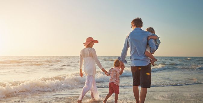 Familie, die einen Strandspaziergang beim Sonnenuntergang macht