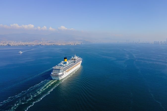 Weißes Kreuzfahrtschiff fährt bei sonnigem Wetter über das Meer