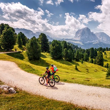 Zwei Personen fahren bei gutem Wetter Fahrrad durch eine Berglandschaft