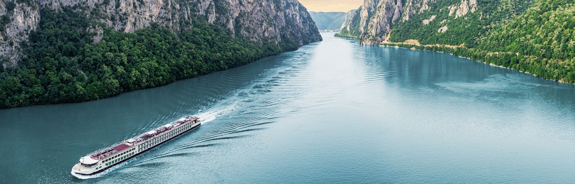 Flusskreuzfahrschiff fährt durch einen Fluss, umgeben von steilen Klippen