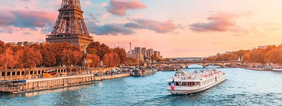 Flusskreuzfahrtschiff auf der Seine neben dem Eiffelturm in Paris