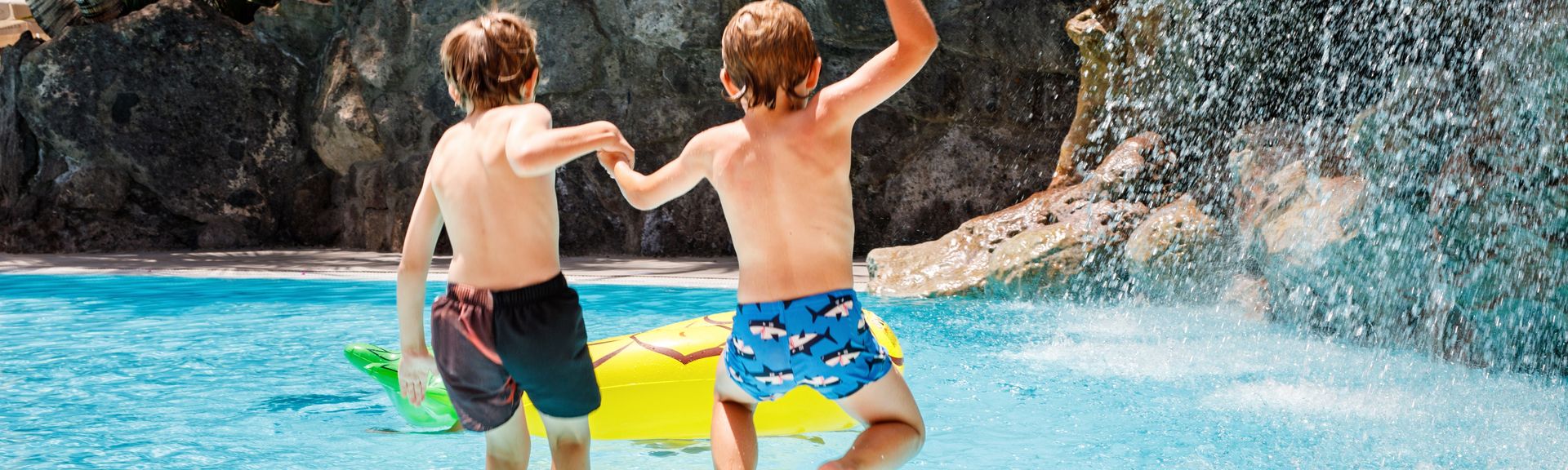 Zwei Jungs springen in einen Pool