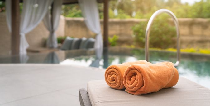 Aufgerollte Handtücher auf einer Liege am Pool