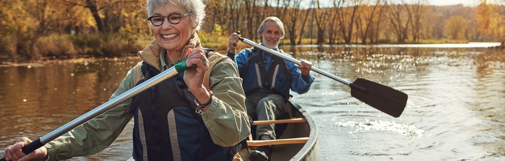 Zwei ältere Personen sitzen lächelnd in einem Kanu