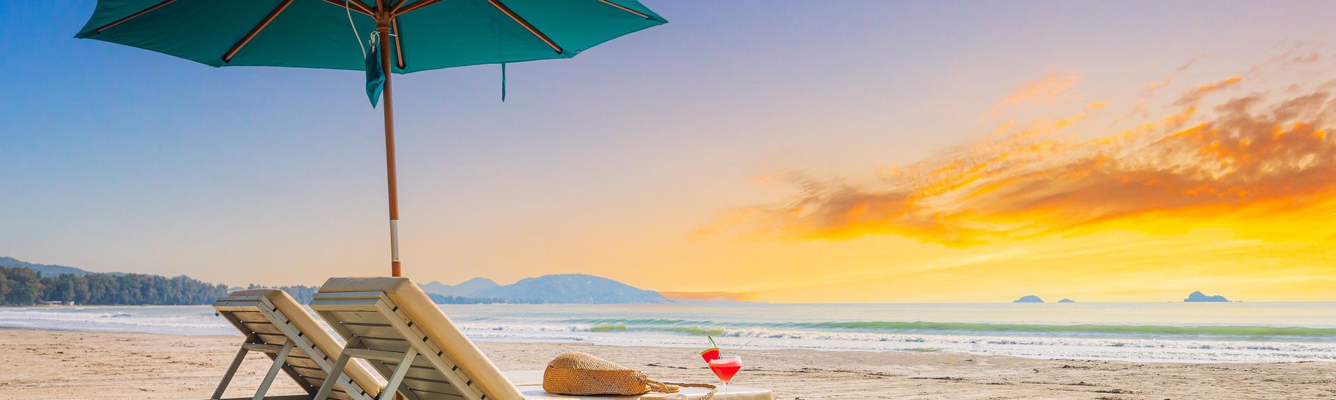 Zwei Liegen mit Sonnenschirm stehen am Strand