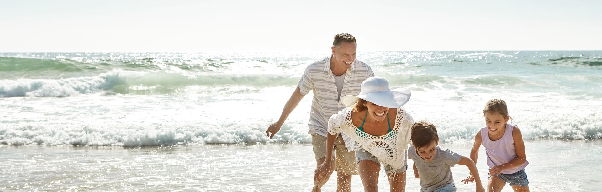 Eine Familie am Strand läuft lachend durch das Wasser