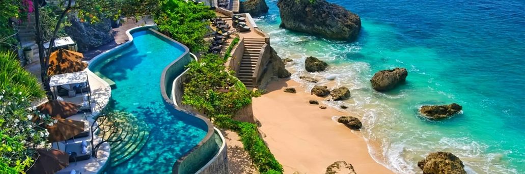 Infinity-Pool auf einer Terrasse oberhalb des Strandes. Unterhalb führt eine Treppe direkt zum Meer