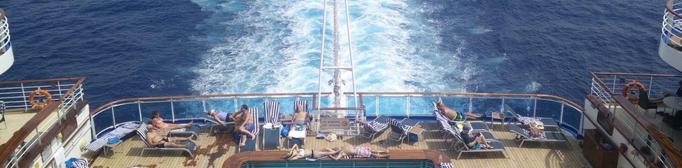 Im Pool am Heck eines Kreuzfahrtschiffes sieht man einige Urlauber schwimmen und sich sonnen