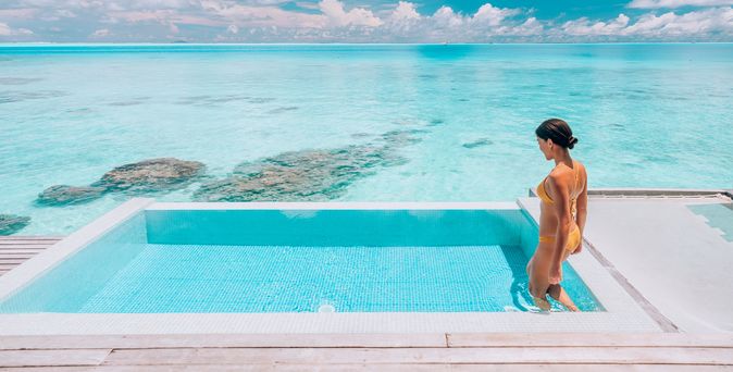 Eine Frau steigt in einen erhöht über dem Strand gelegen Pool