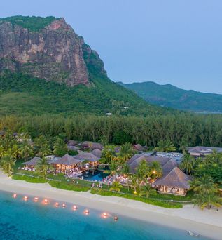 Von Palmen umgebene Hotelanlage auf einer Insel direkt am Strand vor dem Berg Le Morne
