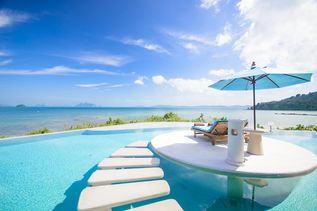 Ein Tisch mit kleinem Sonnenschirm und Getränken steht im Pool