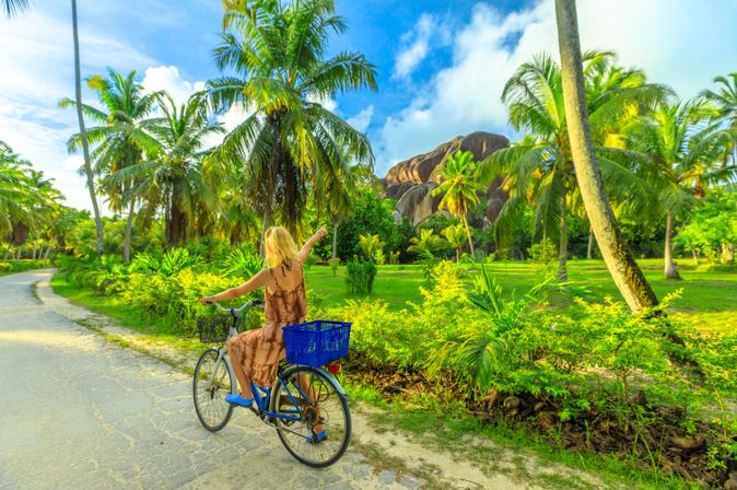 Eine Frau fährt einhändig Fahrrad durch eine grüne Landschaft