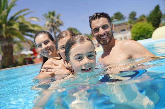 Eine Familie in einem Pool lächelt in die Kamera