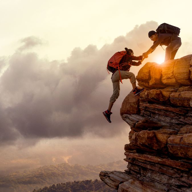 Wanderer bei Sonnenaufgang, Mann hilft Frau einen Berg hoch