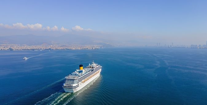 Weißes Kreuzfahrtschiff fährt bei sonnigem Wetter über das Meer