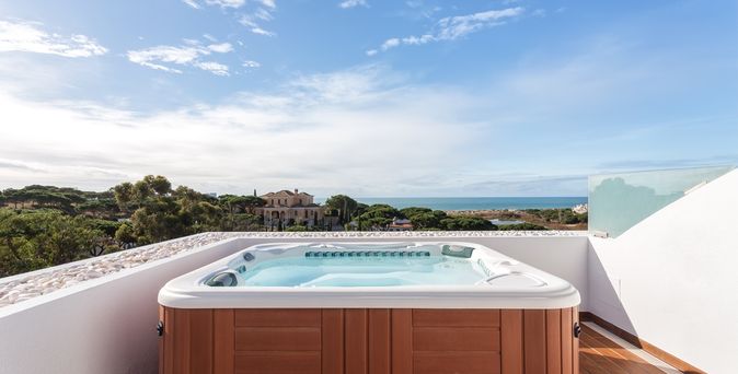 Ein Whirlpool auf einem Balkon mit weißer Brüstung bei Sonnenschein