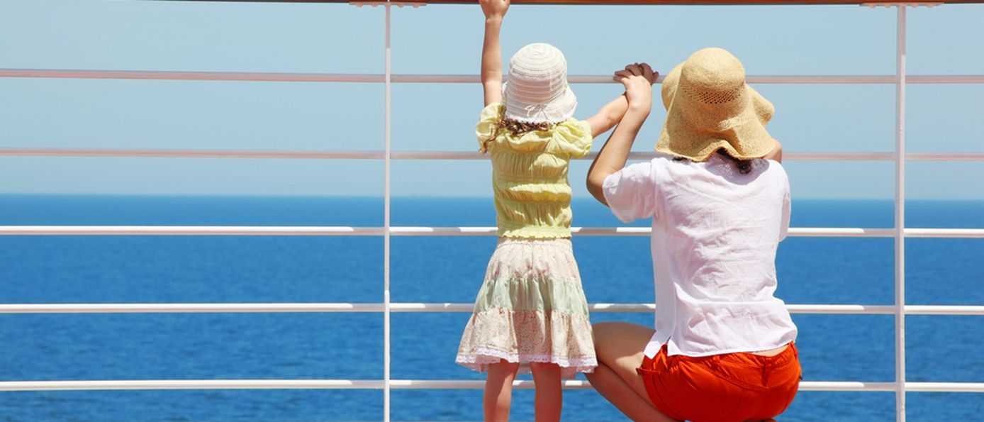 Mutter und Kind stehen an der Reling von einem Kreuzfahrtschiff und schauen auf das Meer