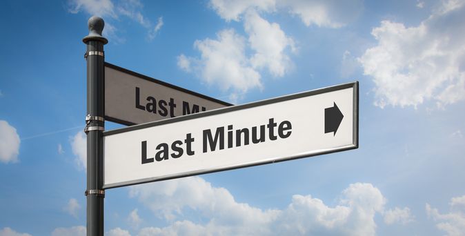Ein Wegweiser mit zwei Schildern, auf beiden steht "Last Minute" mit einem Pfeil