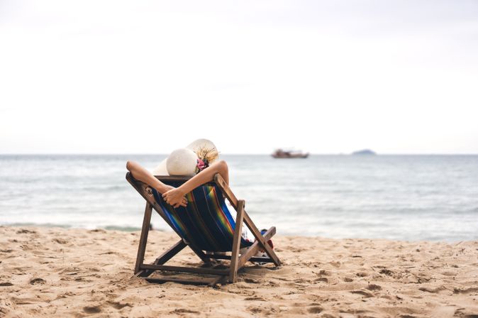 Person am Strand auf einer Liege schaut auf das Meer