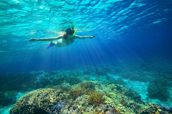 Ein Kind mit Schnorchel im Meer breitet die Arme aus