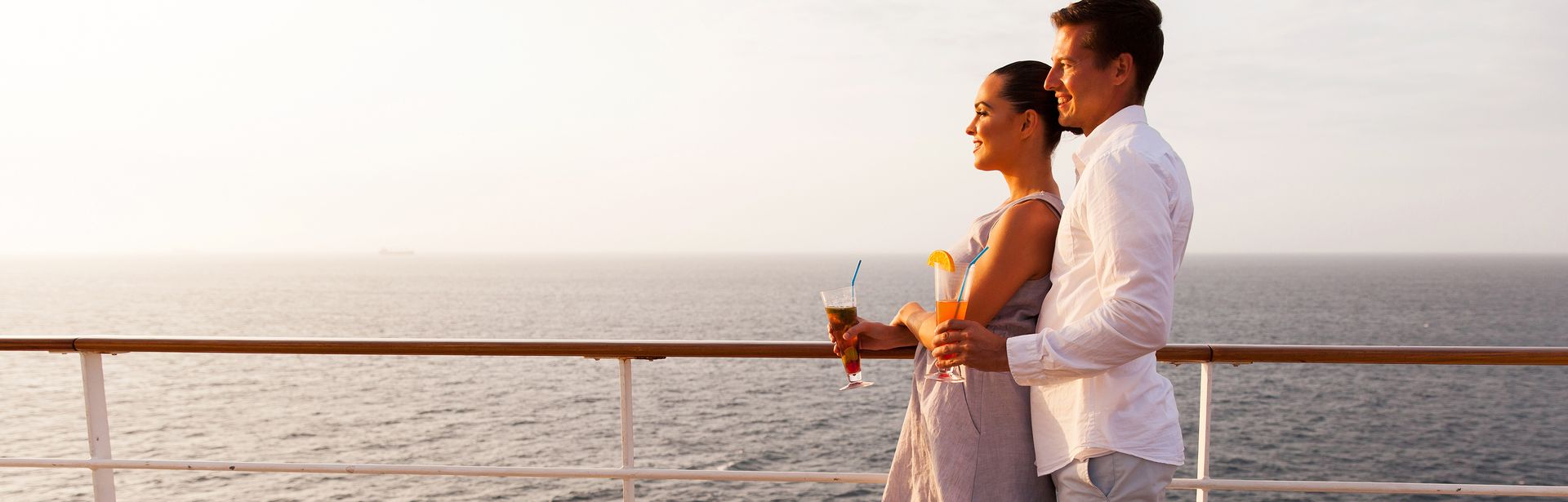 Ein Paar steht auf einem Kreuzfahrtschiff an der Reling und schaut aufs Meer