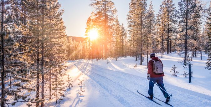 Mann auf Skiern läuft durch eine Schneelandschaft